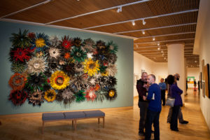 Gallery of art with people admiring and talking.
