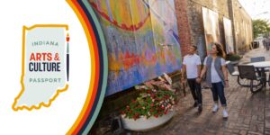 he Indiana Arts and Culture Passport logo represented by a golden color outline of the Indiana state map and a paintbrush on the right side of the map. The text inside the map reads "Indiana Arts & Culture Passport." Next to the logo is a photo of a young couple appreciating vibrant paintings mounted along the wall in an alley.